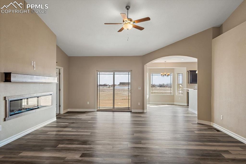 Image 3 of 45: Unfurnished living room featuring baseboards, arched walkways, vaulted ceil