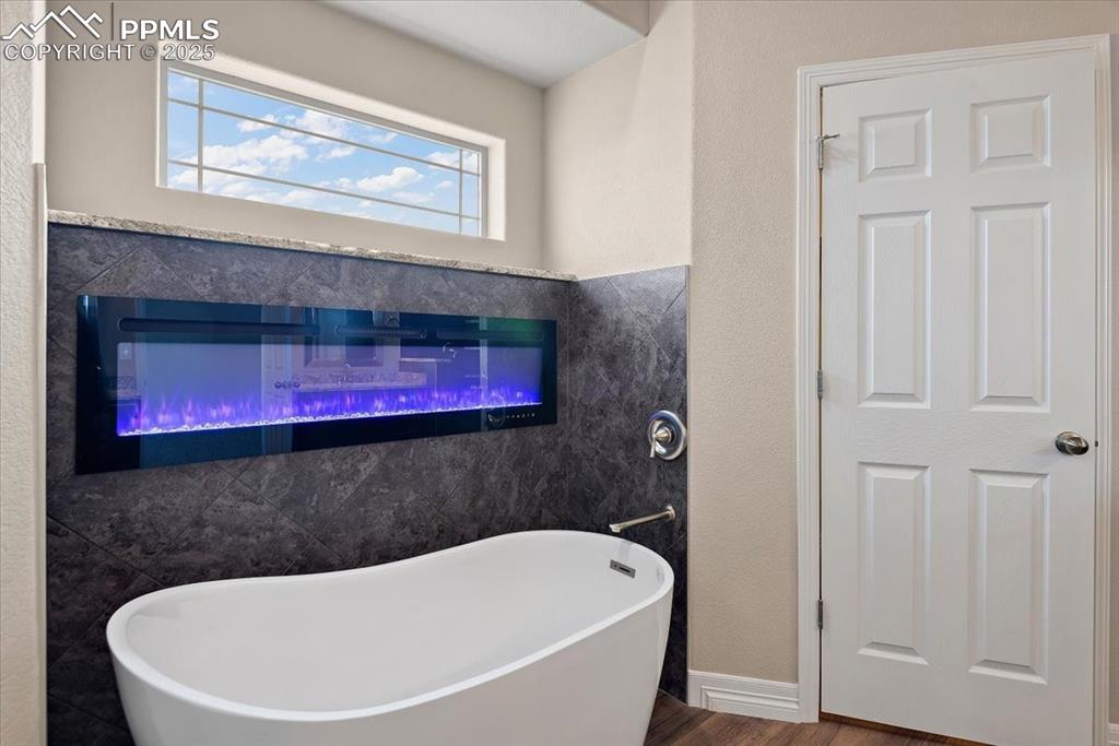 Image 31 of 45: Full bath with a freestanding bath and wood finished floors