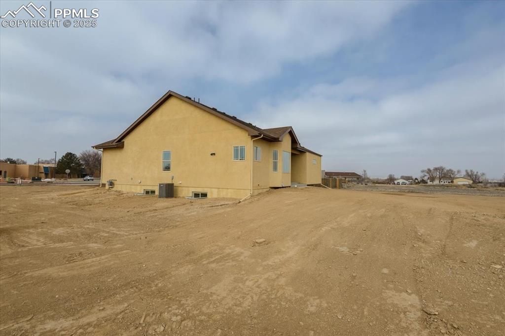 Image 42 of 45: View of side of property featuring cooling unit and stucco siding