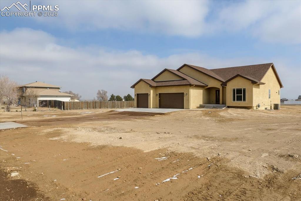 Image 44 of 45: View of front of property with an attached garage, fence, and stucco siding