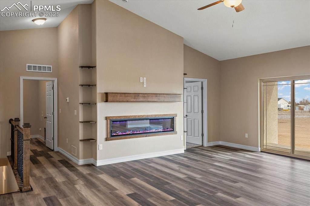 Image 9 of 45: Unfurnished living room with visible vents, dark wood-type flooring, a glas