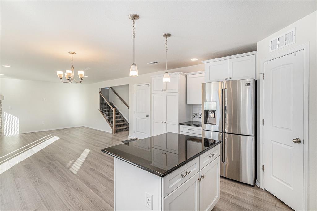 Image 13 of 33: Kitchen featuring stainless steel fridge with ice dispenser, hanging light