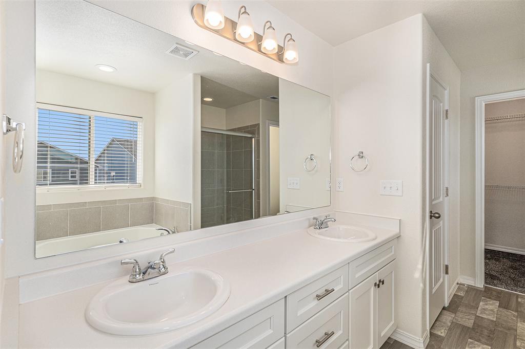 Image 25 of 33: Full bath featuring a bath, a spacious closet, a stall shower, double vanit