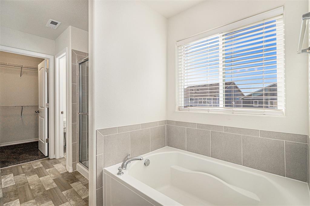 Image 26 of 33: Bathroom with a spacious closet, a garden tub, and a stall shower