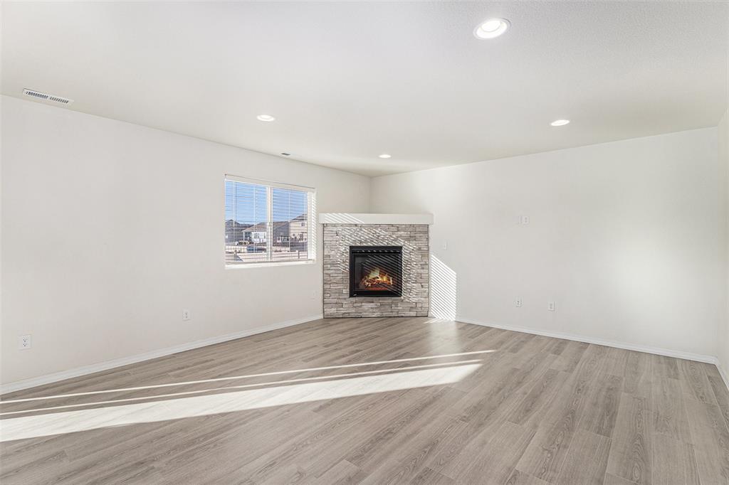 Image 4 of 33: Unfurnished living room with light wood-style flooring, a fireplace, and re