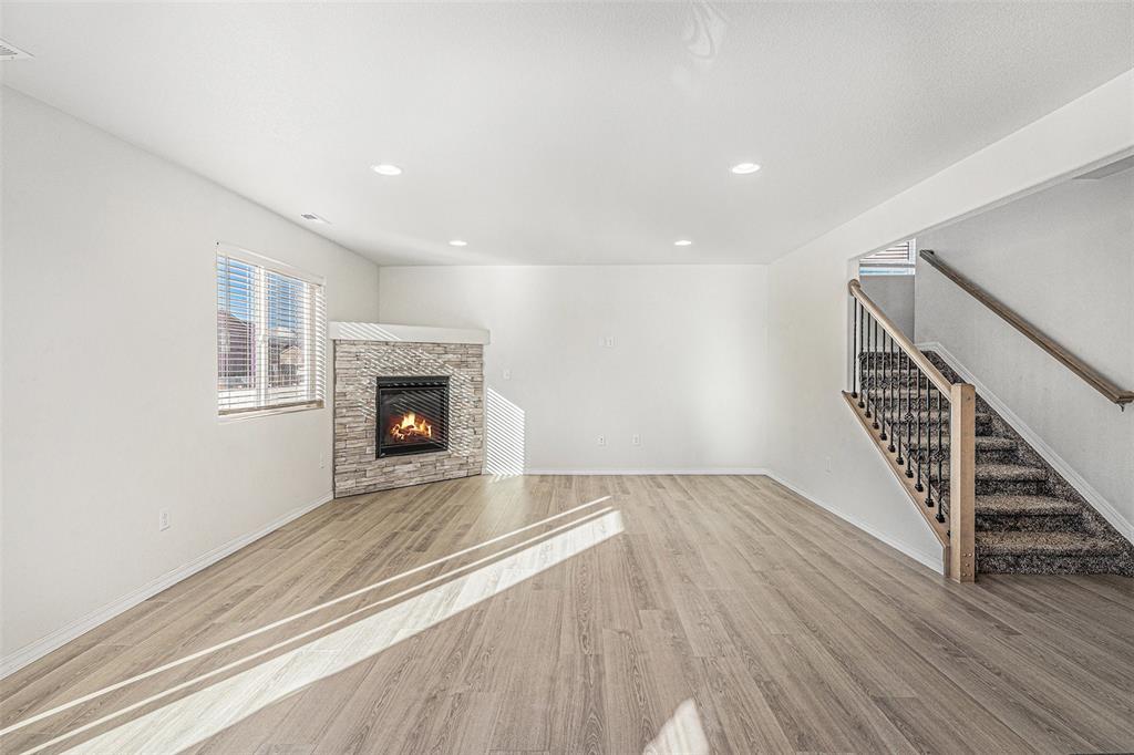 Image 5 of 33: Unfurnished living room featuring stairway, light wood-type flooring, a sto