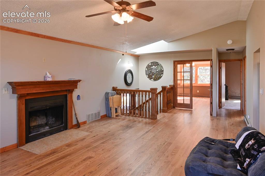 Image 12 of 40: Wood-finish flooring throughout, fireplace with a wood mantel, wood balustr