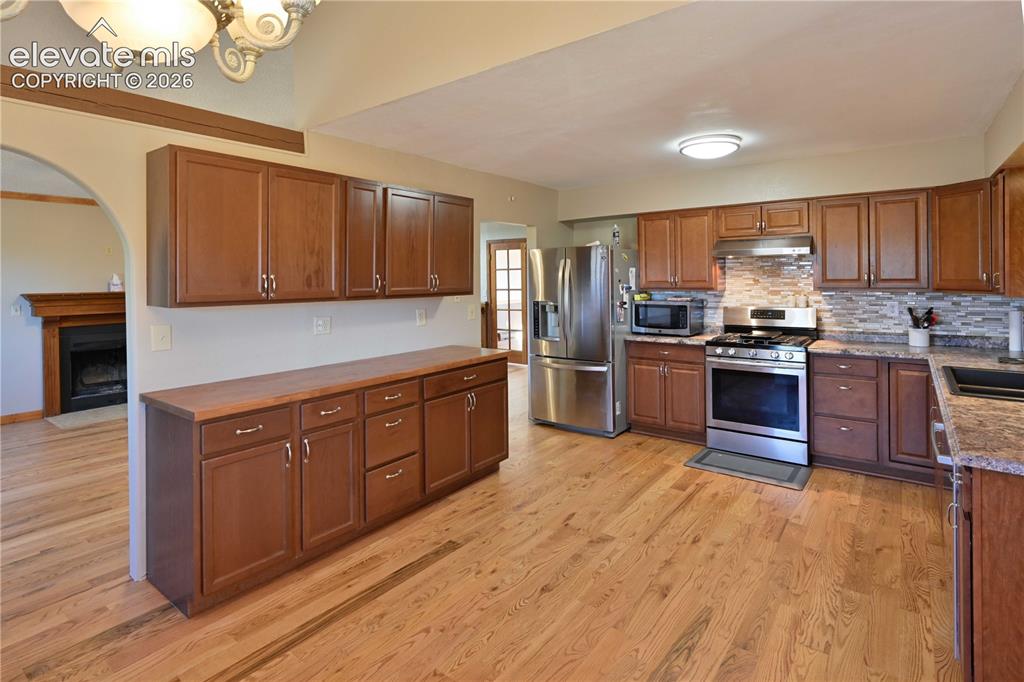 Image 15 of 40: Kitchen featuring wood-finish flooring, abundant wood cabinetry, stainless 