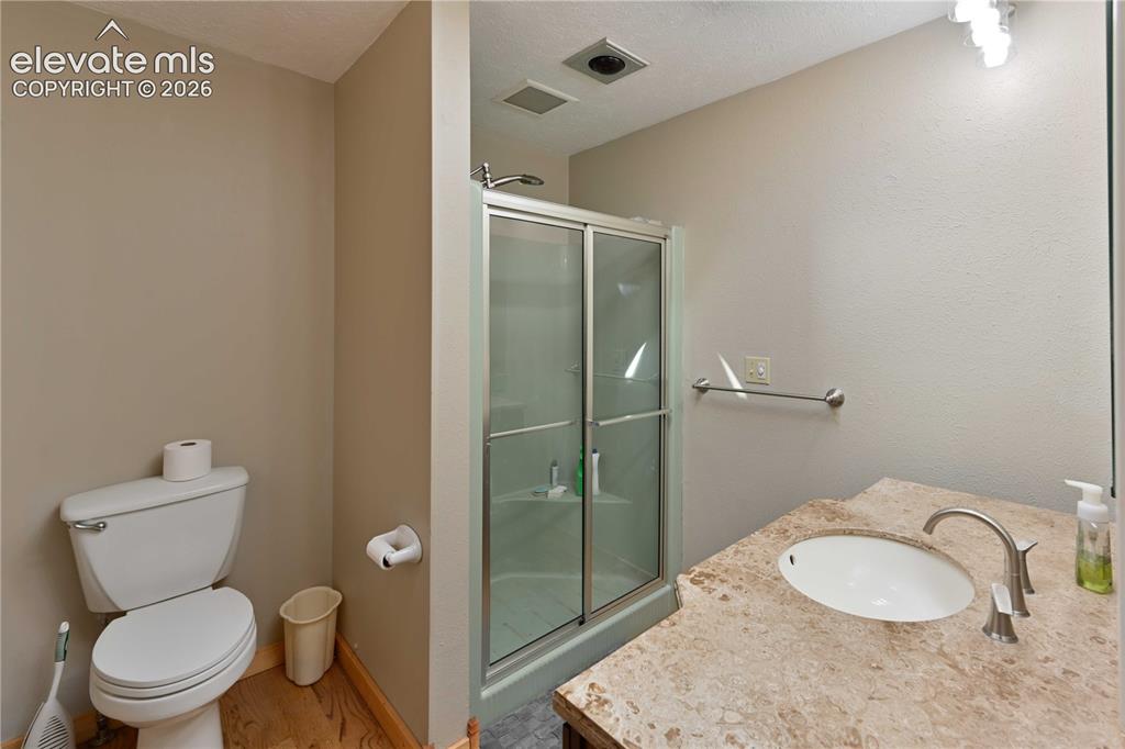 Image 21 of 40: Full bathroom featuring a white toilet, enclosed shower with sliding glass 
