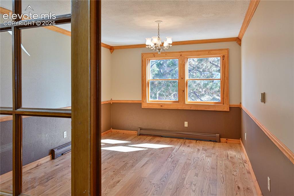 Image 22 of 40: Hardwood flooring, wood window trim, chandelier lighting, wainscoting, and 