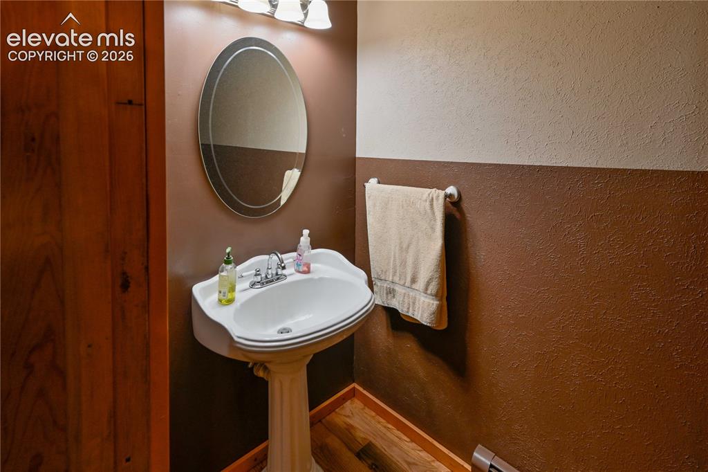 Image 23 of 40: Pedestal sink with chrome faucet, oval mirror, and three-bulb vanity light