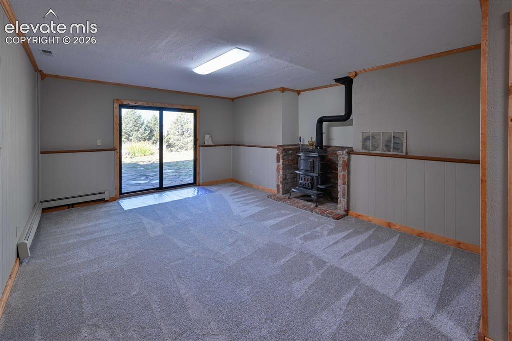 Image 26 of 40: Spacious room featuring gray wall paneling, a sliding glass door, a brick-s