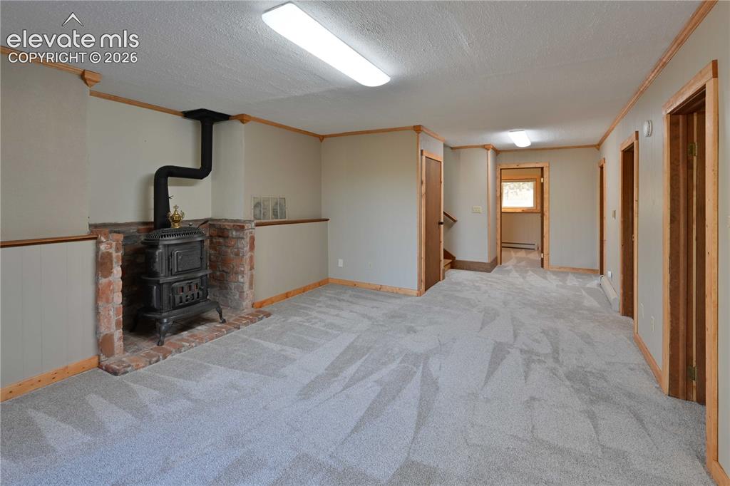 Image 27 of 40: Spacious room featuring a cast iron stove with a brick surround, light-colo
