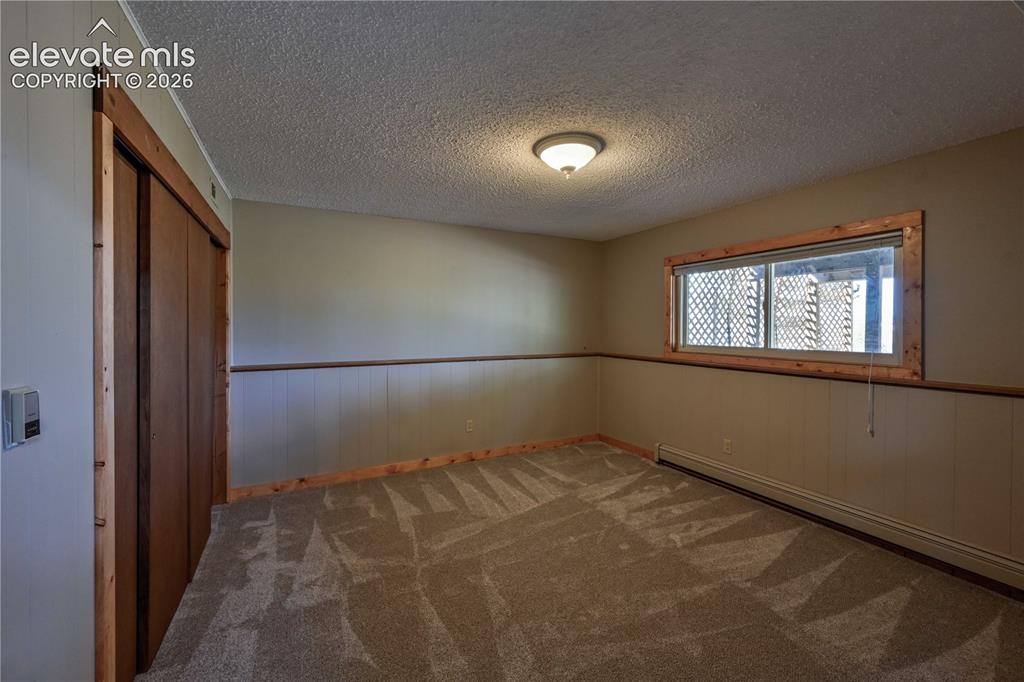 Image 30 of 40: Carpeted flooring, paneled wainscoting, wood-finish trim, window, and flush