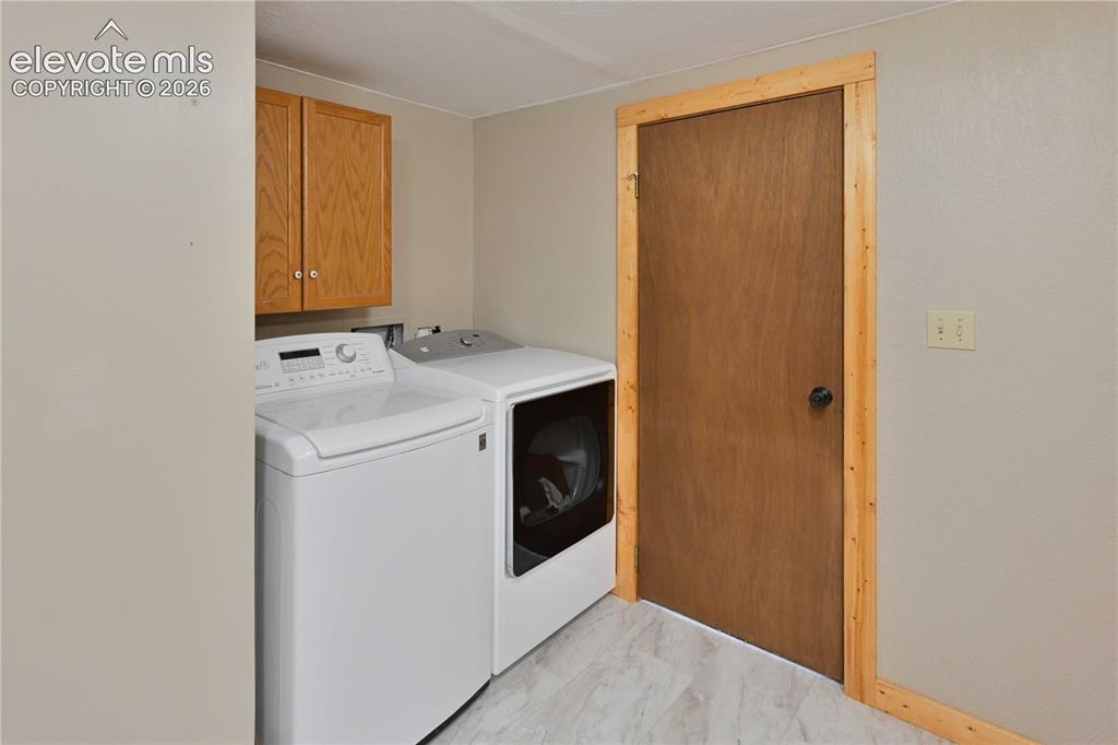 Image 32 of 40: Laundry area featuring wood-finish cabinetry, light-toned wall paint, a sol
