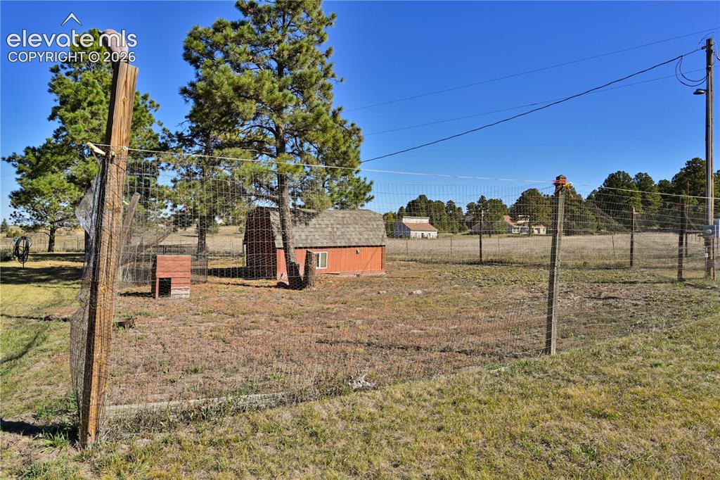 Image 37 of 40: Expansive fenced outdoor area featuring a red utility shed with an asphalt