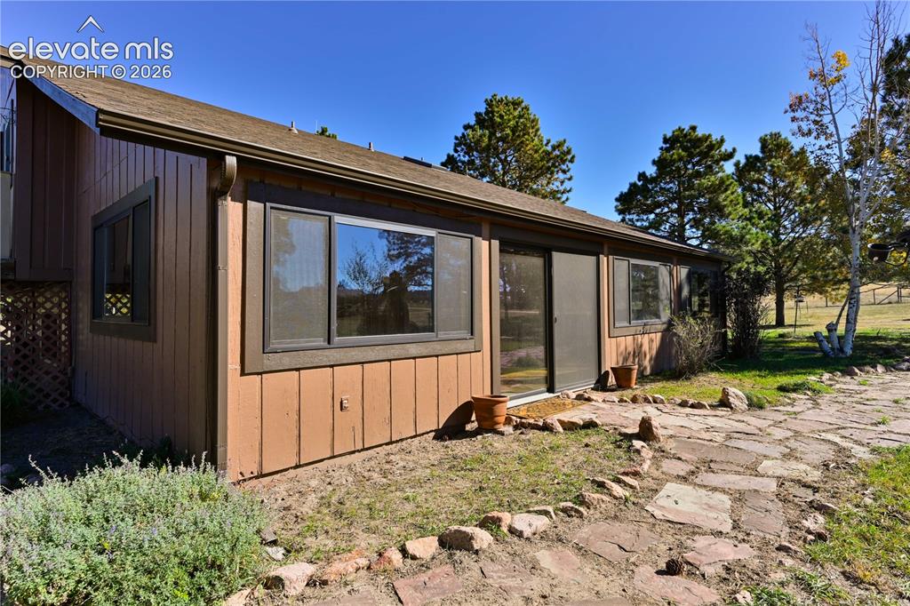 Image 4 of 40: Board and batten siding, multiple windows, sliding glass door, shingled roo