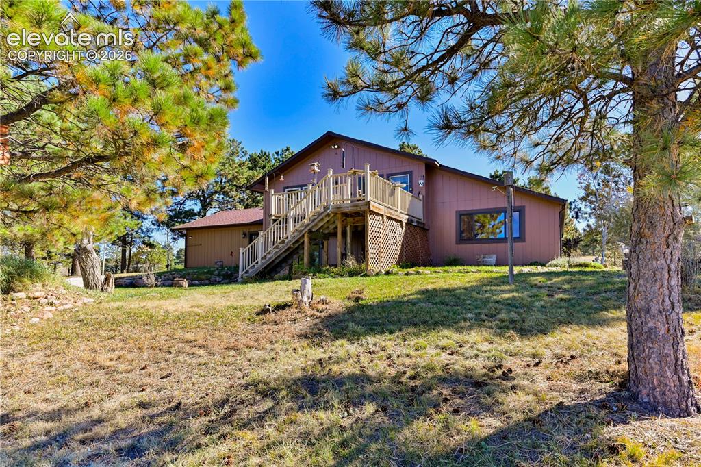 Image 5 of 40: Expansive exterior featuring a large wooden deck with staircase, sloped lan