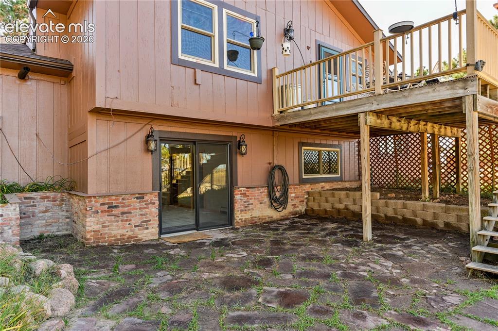 Image 7 of 40: Walk-out patio with flagstone paving and a two-story wood deck