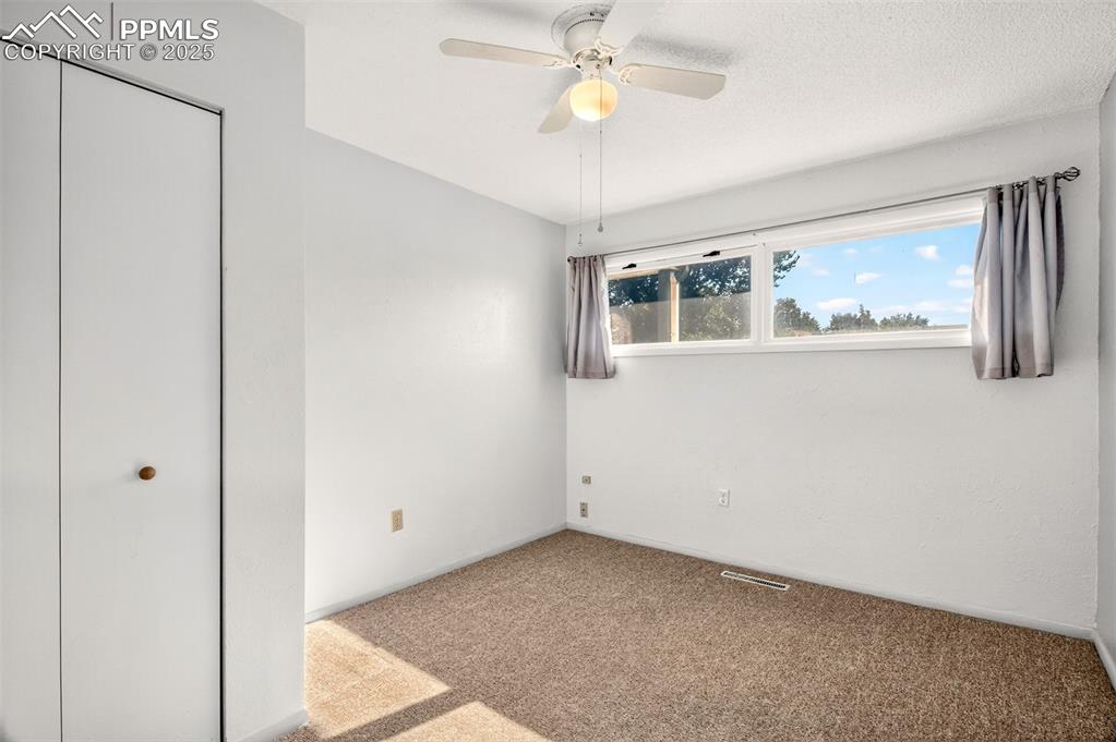 Image 12 of 21: Main Level Bedroom #3 With Ceiling Fan, Hardwood Floor Under The Carpet