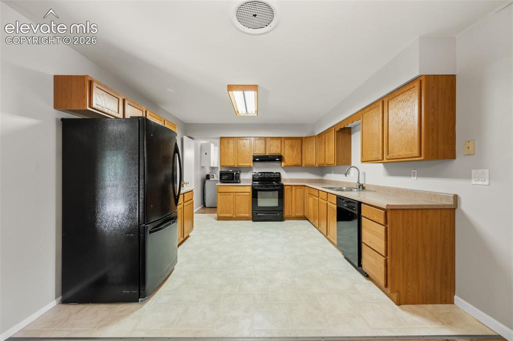 Image 11 of 36: Kitchen featuring wood-finish cabinetry, laminate countertops, and essentia