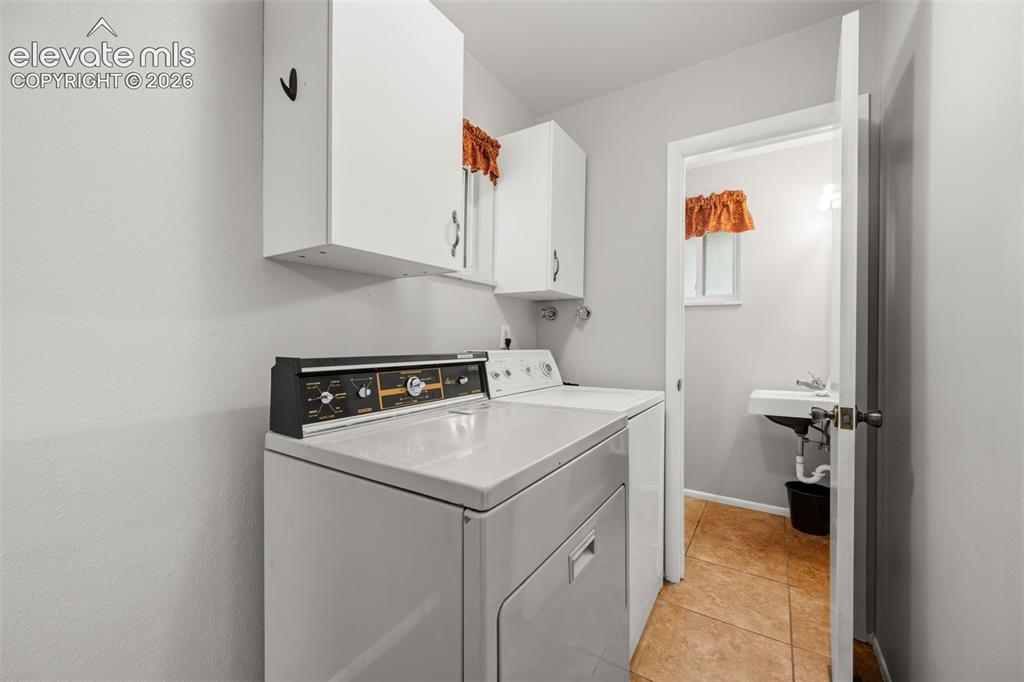 Image 13 of 36: Dedicated laundry area featuring white upper cabinetry and light gray walls
