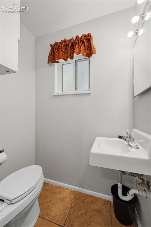 Image 14 of 36: Powder room featuring a wall-mounted sink, ceramic tile flooring, and a win