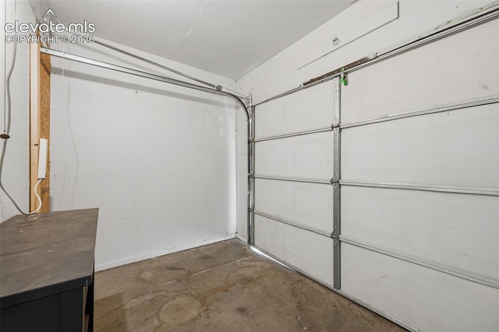 Image 17 of 36: Interior garage space featuring a paneled garage door and concrete flooring