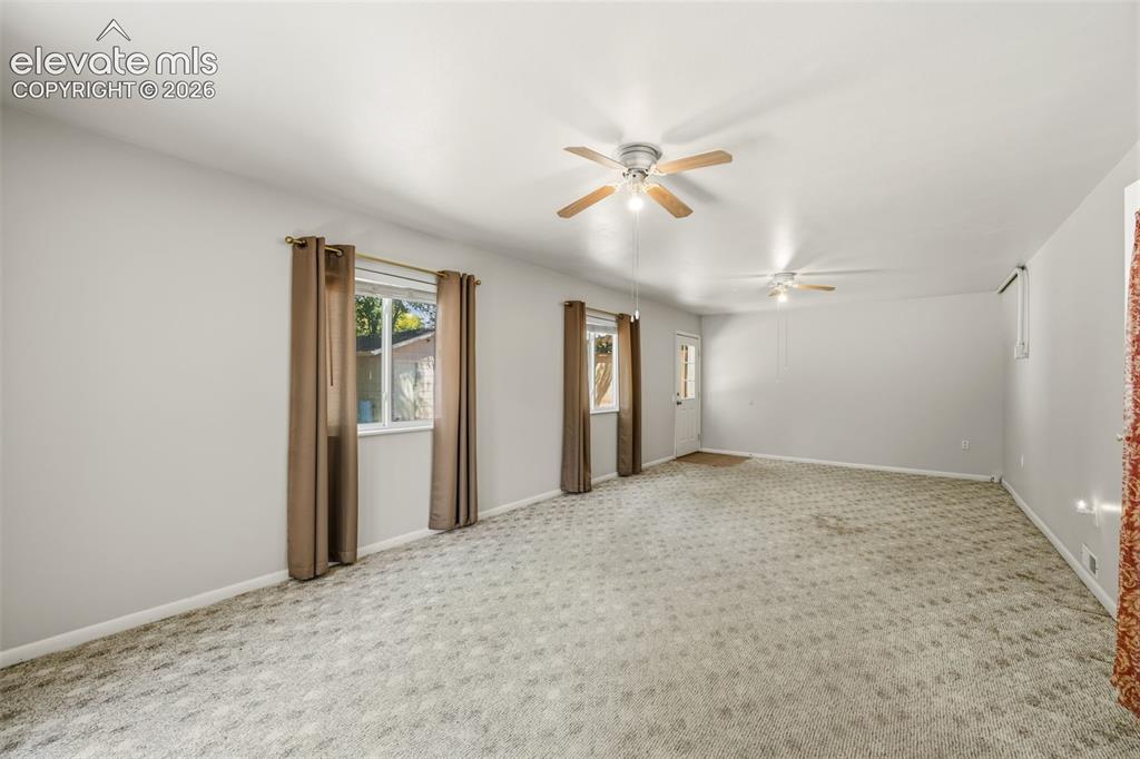 Image 18 of 36: Spacious room featuring light-colored walls, patterned carpeting, and multi