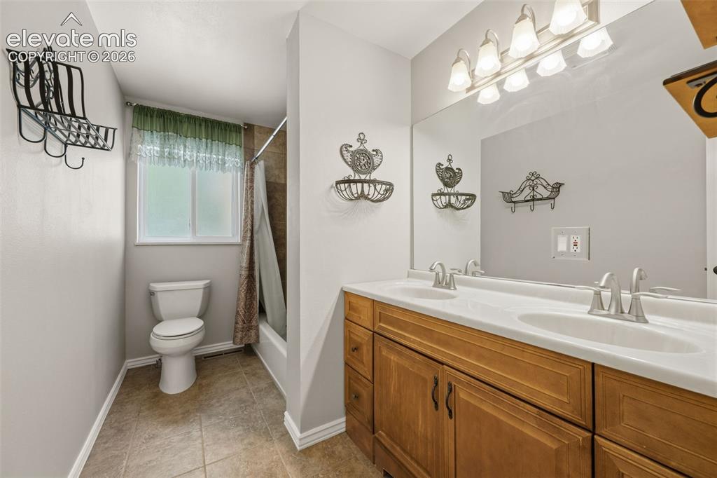 Image 21 of 36: Bathroom featuring a dual vanity with wood cabinetry and a white countertop