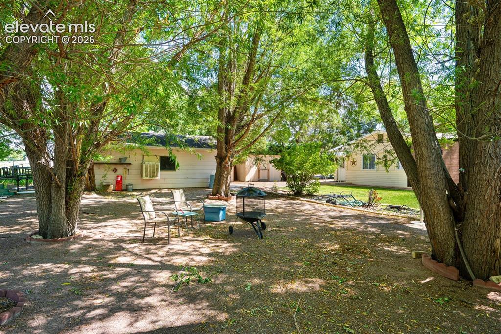 Image 32 of 36: Expansive outdoor area featuring mature trees, a gravel ground cover, and a