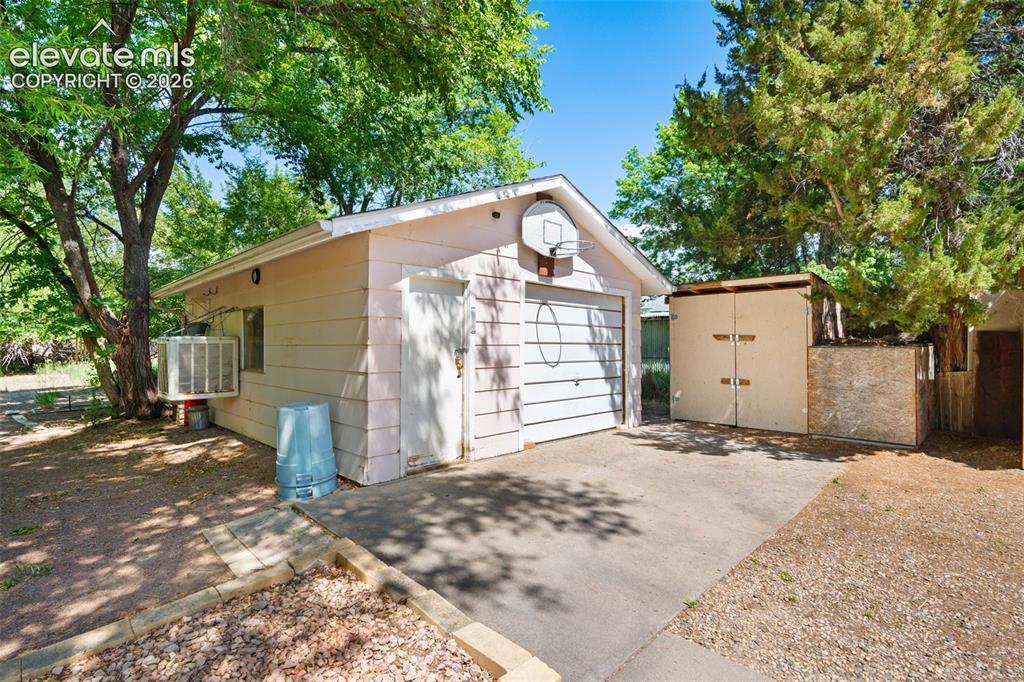 Image 33 of 36: Detached garage structure featuring a white panel garage door, a side entry