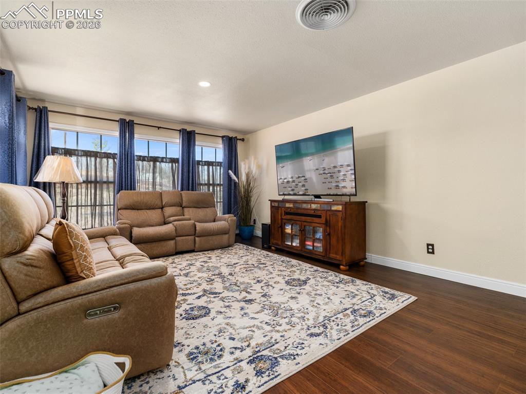 Image 10 of 39: Living area featuring dark wood-type vinyl flooring and recessed lighting, 