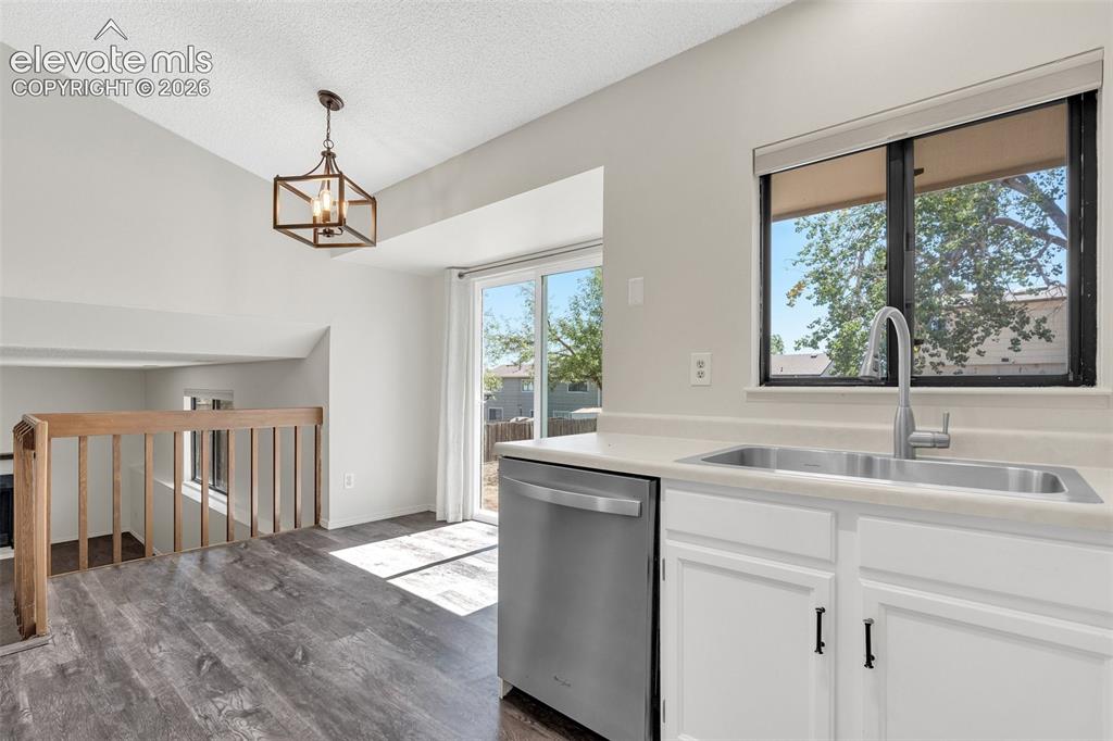 Image 10 of 33: Vaulted ceiling with an open-cage chandelier, wood-finish flooring, white c