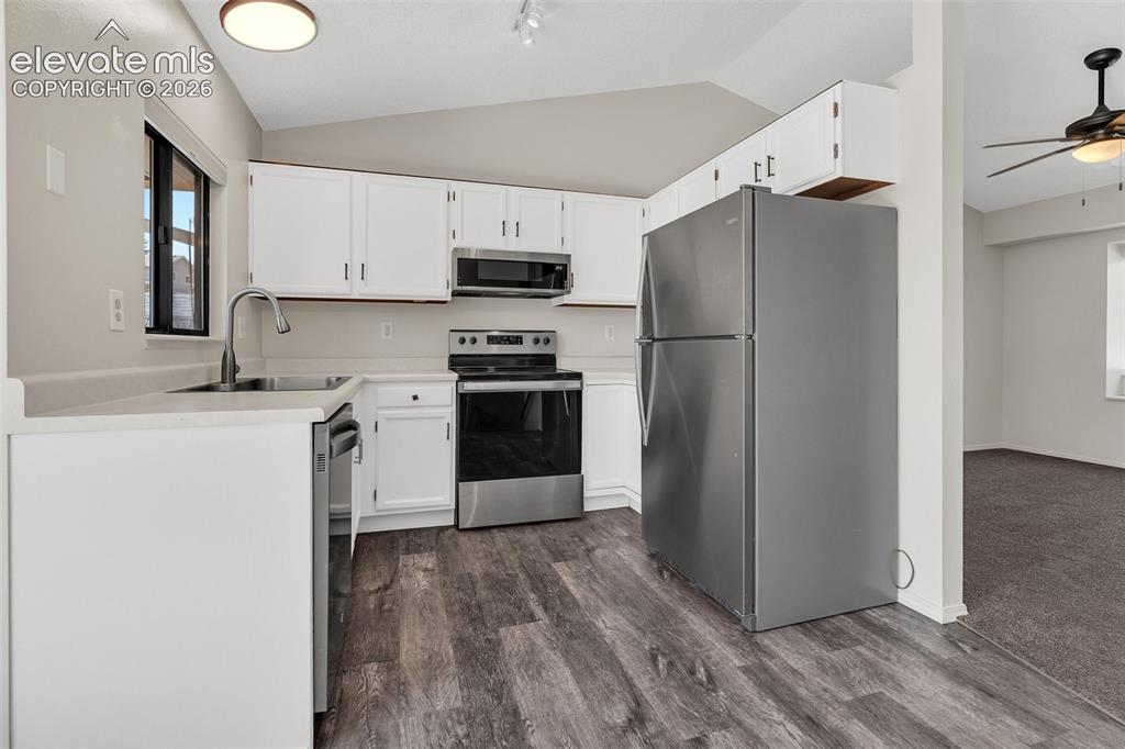 Image 12 of 33: White cabinetry, stainless steel appliances, wood-finish flooring, light-co