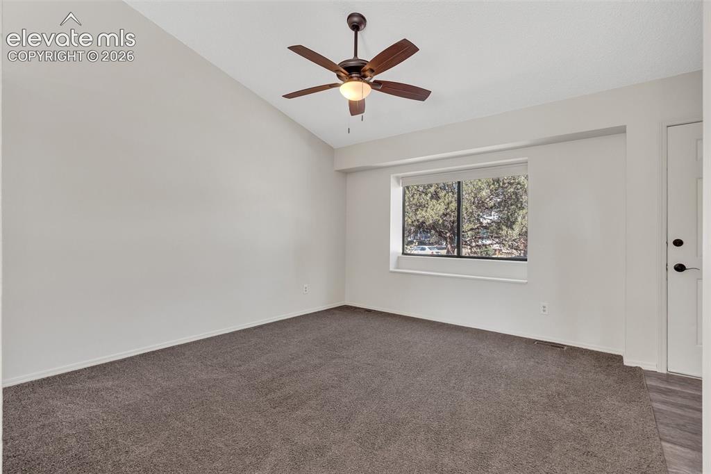 Image 13 of 33: Vaulted ceiling with a ceiling fan, neutral wall tones, a window with exter