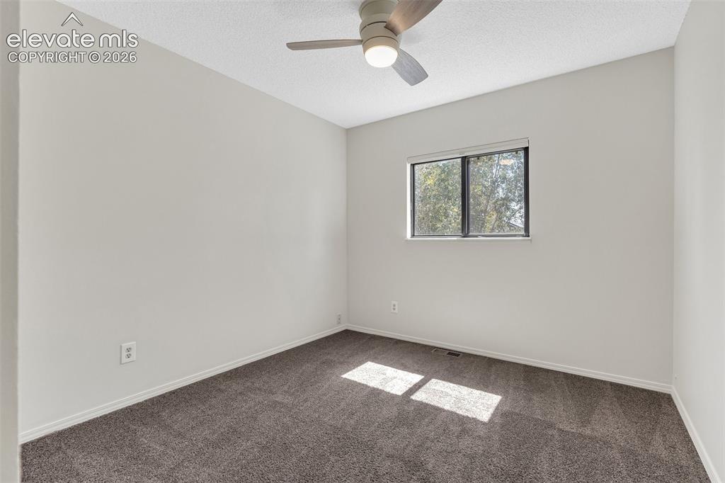 Image 19 of 33: Neutral wall finishes, textured ceiling, window with white blinds, grey car