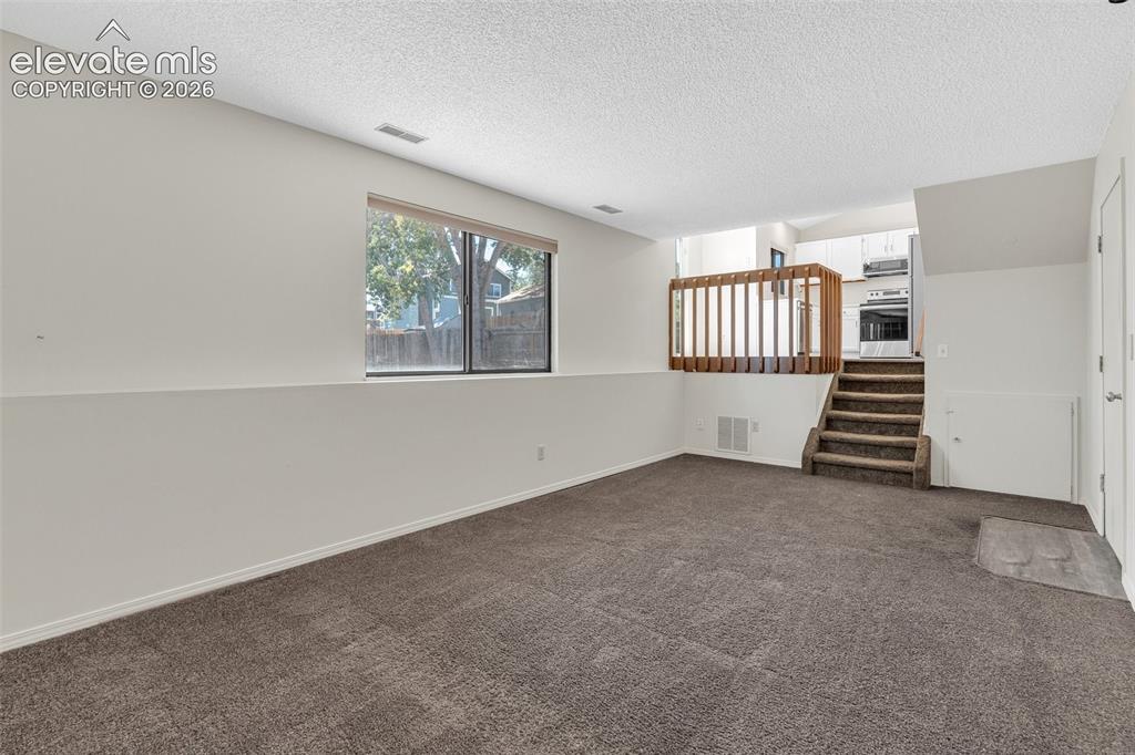 Image 25 of 33: Spacious carpeted area with a large window, providing natural light