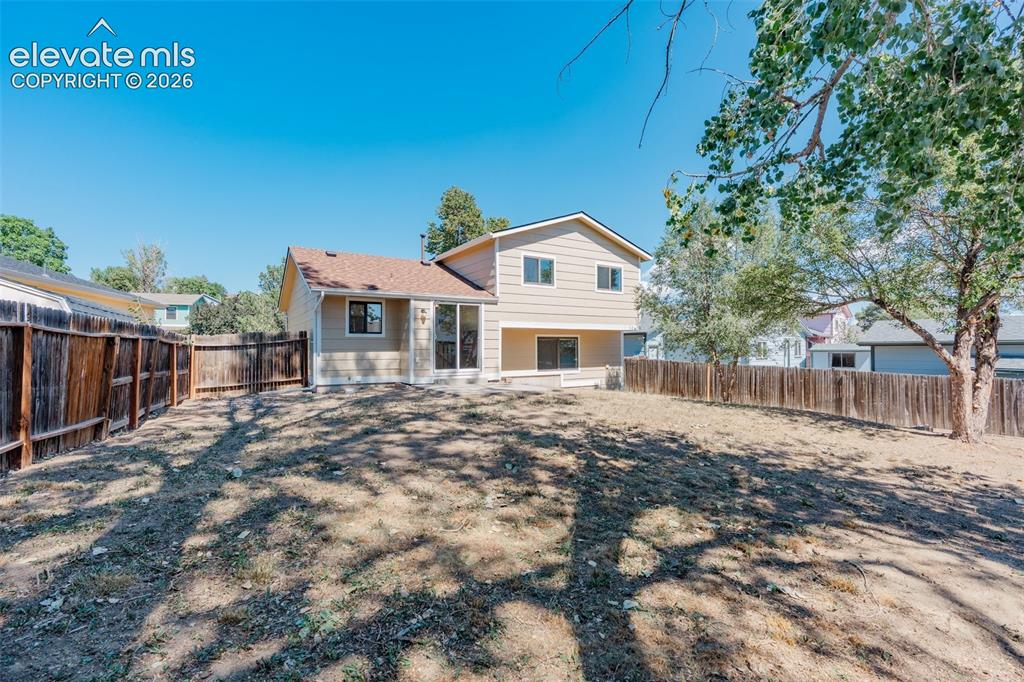 Image 29 of 33: Expansive fenced yard with a multi-level structure featuring a main level p
