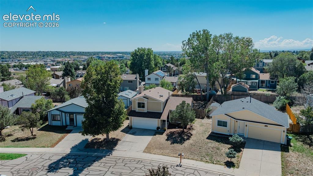 Image 31 of 33: Residential street with mature trees and a distant urban landscape