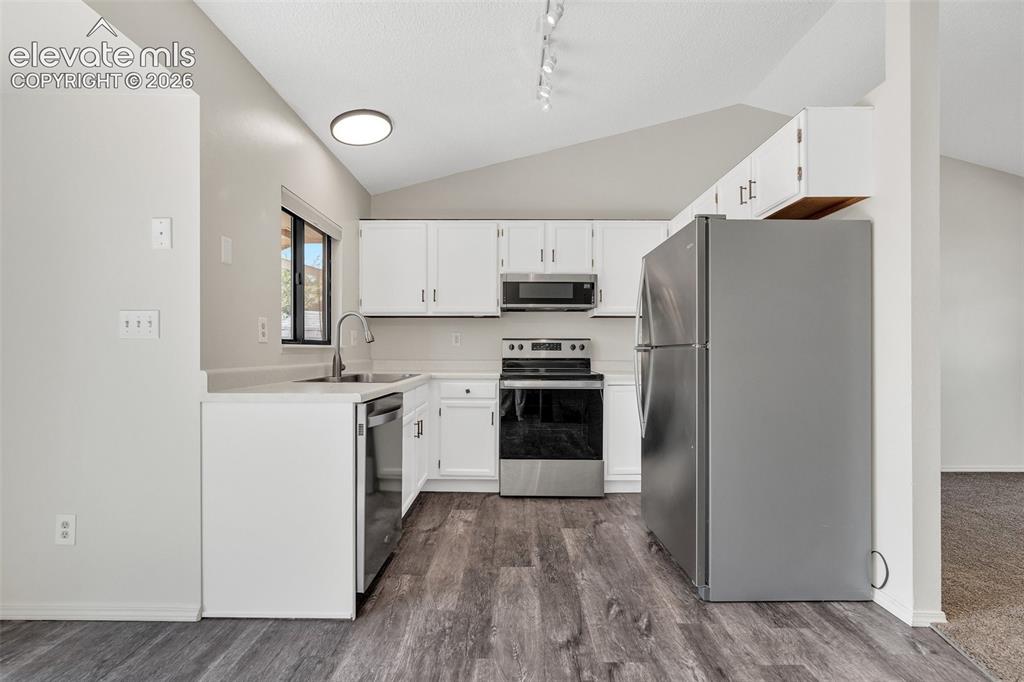 Image 9 of 33: Kitchen featuring white cabinetry, stainless steel appliances, wood-finish 