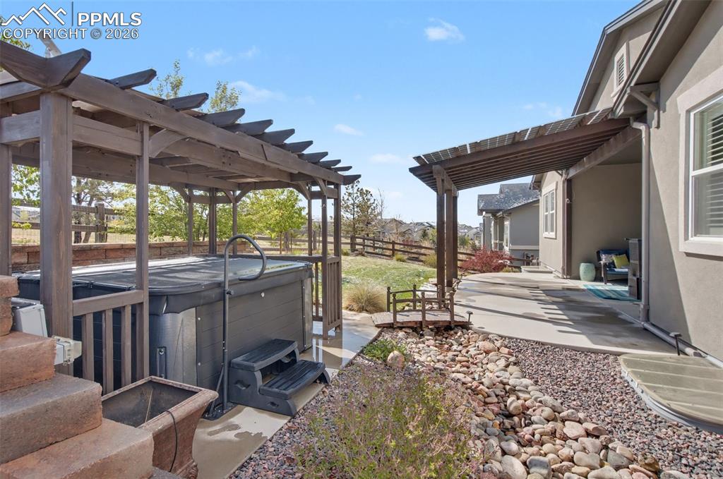 Image 39 of 50: Covered back patio featuring custom solar setup for the roof and hot tub un