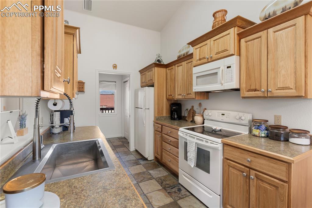 Image 8 of 27: The kitchen has beautiful cabinetry and an oversized farm sink.  It is adja