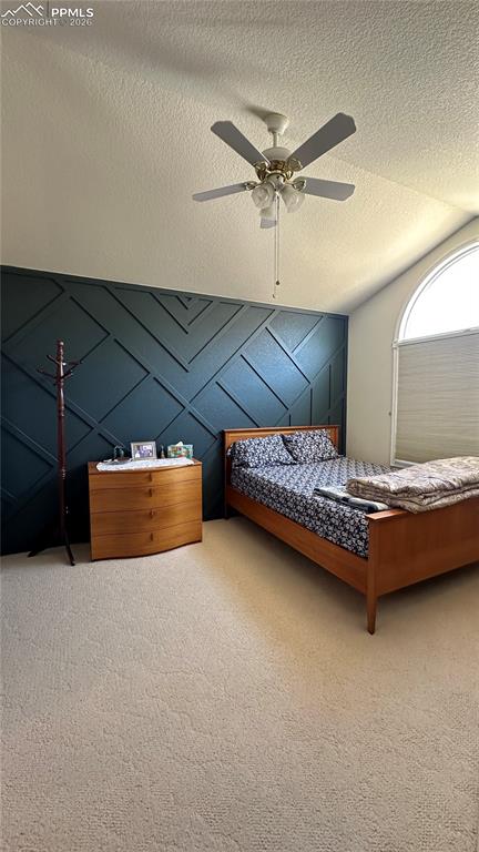 Image 32 of 38: Carpeted bedroom with lofted ceiling, ceiling fan, and a textured ceiling