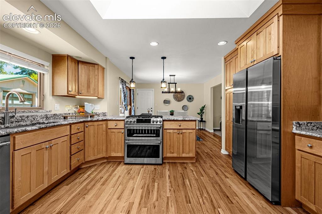 Image 11 of 38: Modern kitchen featuring wood-finish flooring, light wood cabinetry, stone
