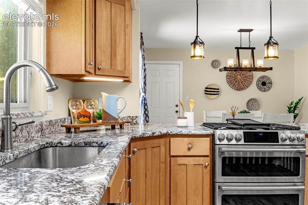 Image 12 of 38: Kitchen featuring wood cabinetry with knob hardware, stainless steel sink w