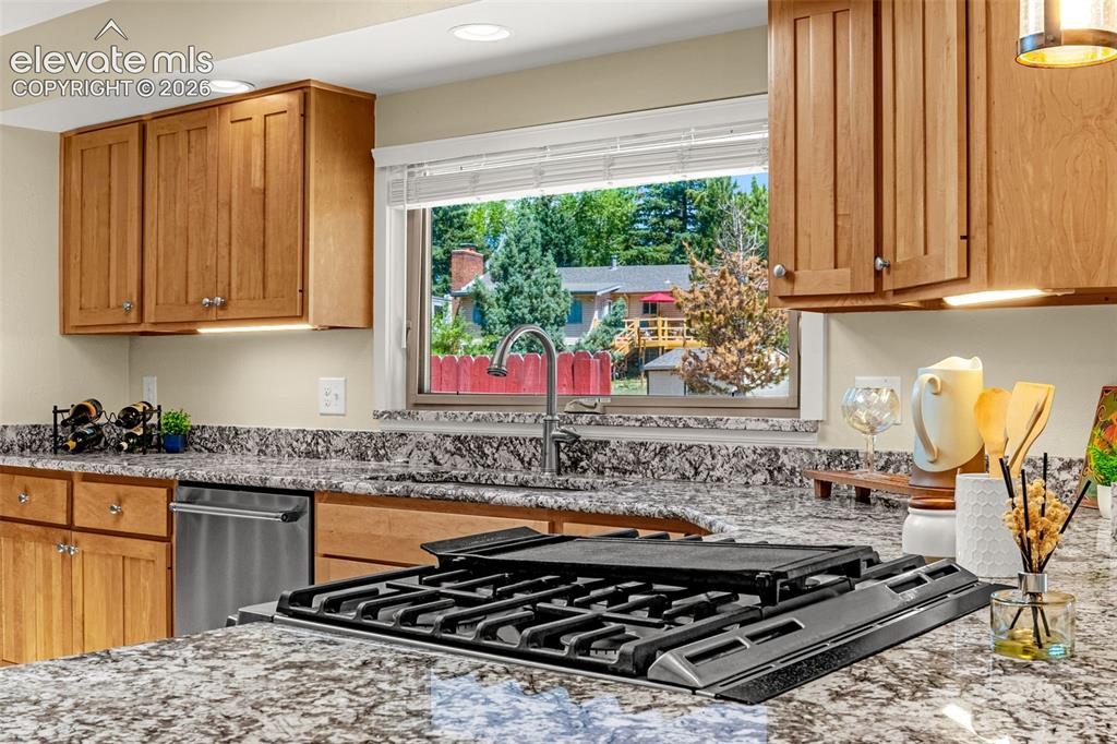 Image 13 of 38: Kitchen featuring a built-in gas cooktop, granite countertops, wood cabinet