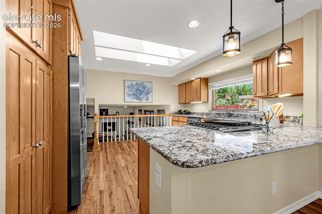 Image 14 of 38: Kitchen featuring a granite island with an integrated cooktop, wood-finish