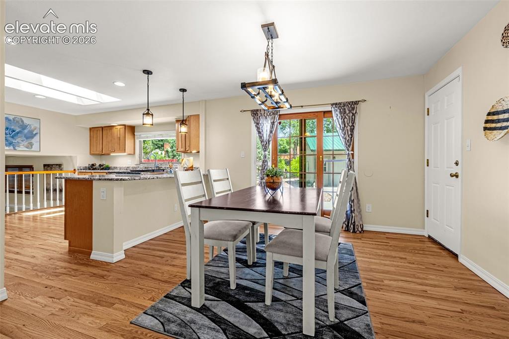 Image 15 of 38: Dining area with hardwood-finish flooring, a contemporary chandelier, and a