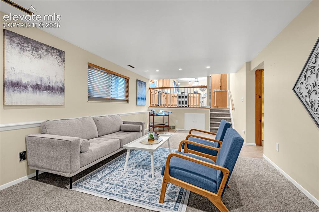 Image 22 of 38: Carpeted entertainment space featuring a window with wood-finish blinds, li